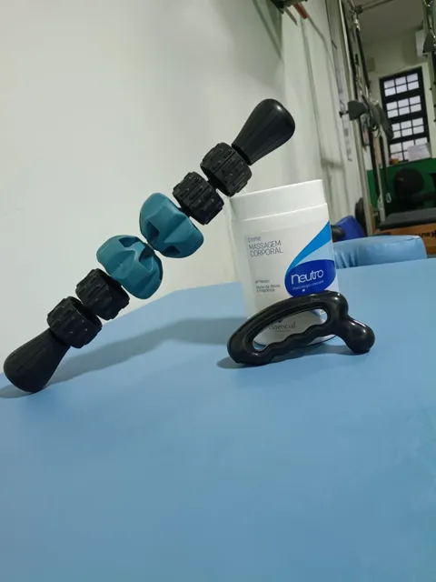Bastão de rolos, ferramenta de liberação miofascial e creme de massagem usados nas sessões de massoterapia do estúdio.